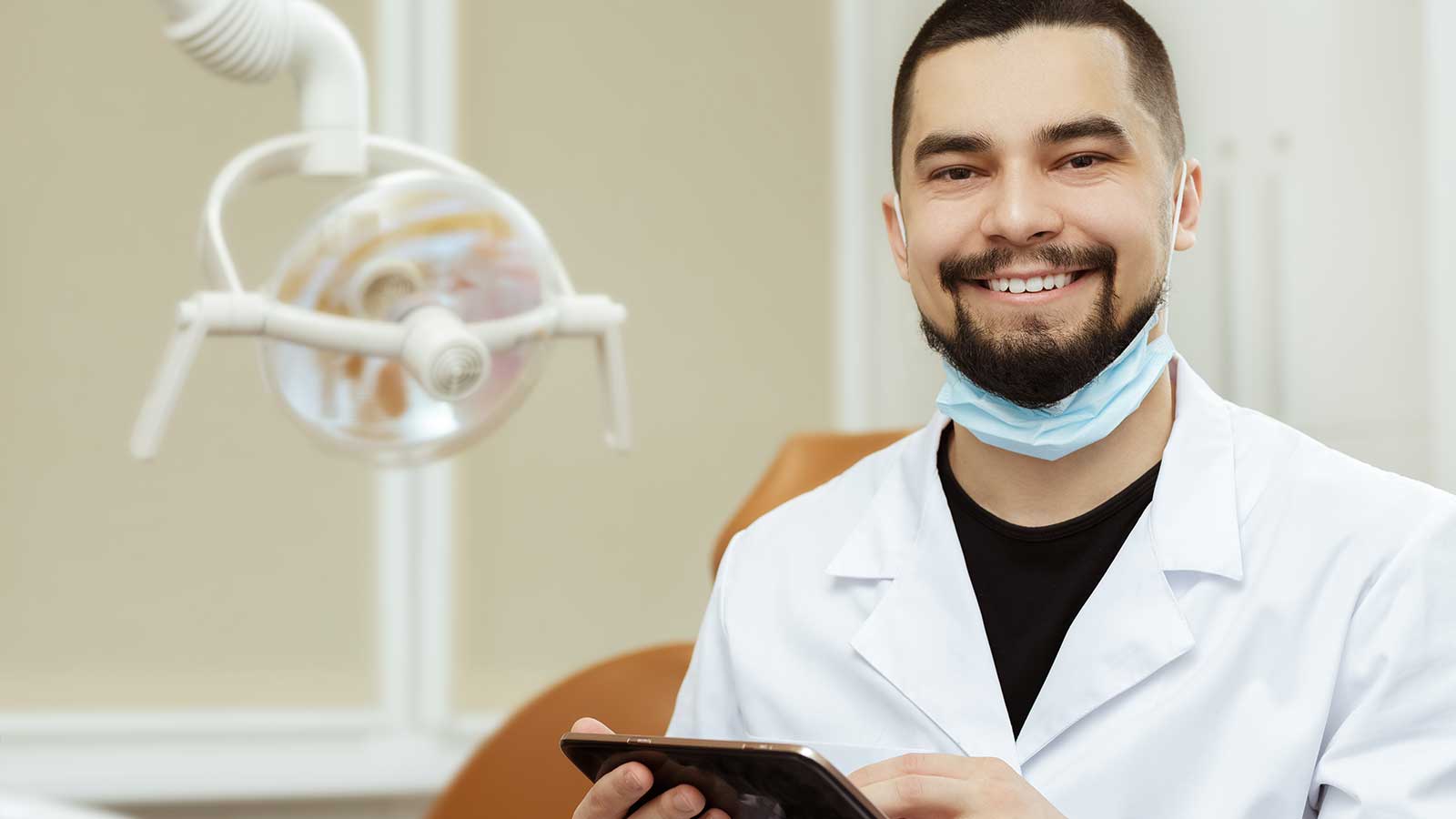 Dentist in clinic smiling using tablet