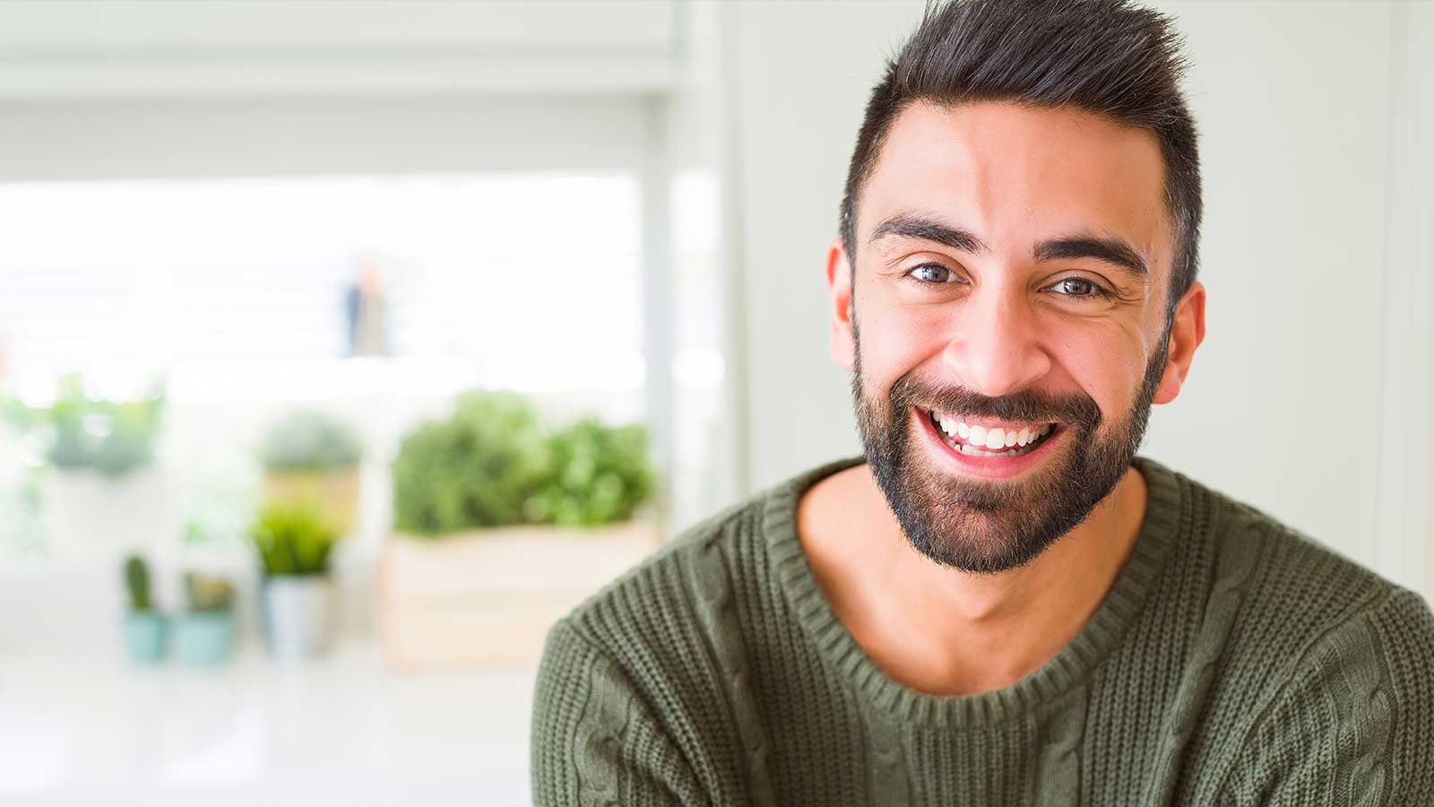 Man smiling at home with green jumper on