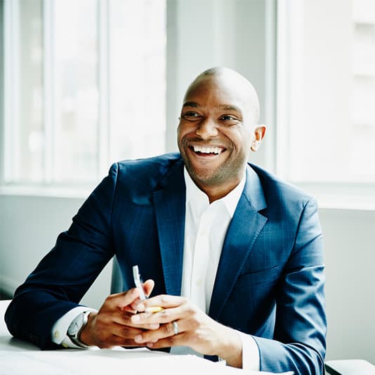 Man wearing suit smiling at desk