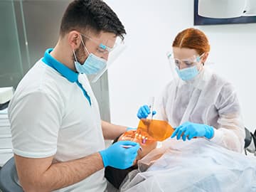Dentist and dental assistant wearing PPE and working on a patient
