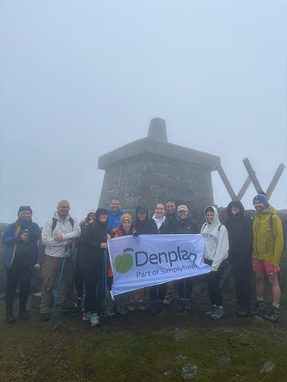 Dentists posing with a Denplan banner on a misty hillside