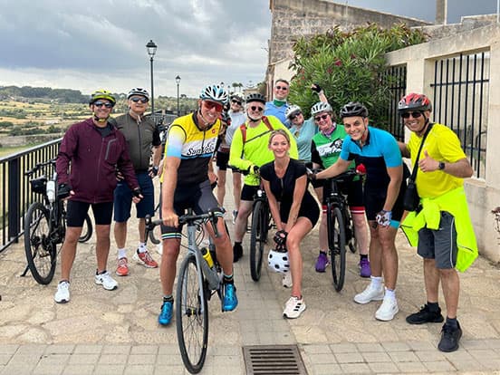 Denplan dentists smiling and posing together with their bicycles in a sunny outdoor setting