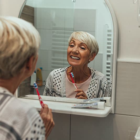 Woman brushing her teeth in the bathroom mirror