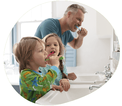 Father and two children brushing their teeth in bathroom
