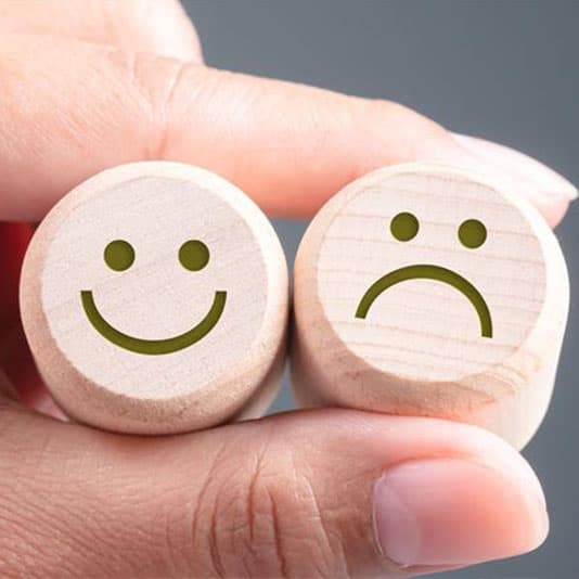 Happy and sad faces held between fingers