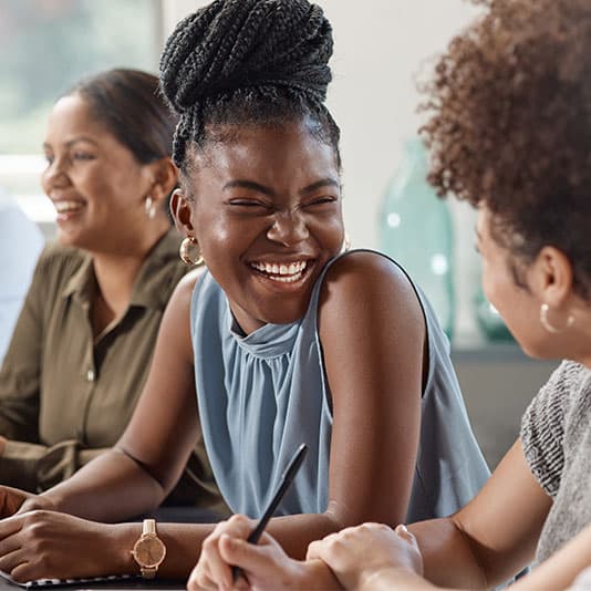 Woman sat with colleagues at table smiling