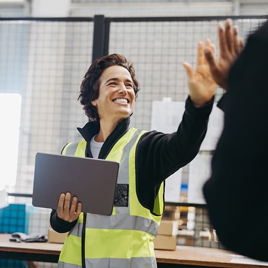 Female factory worker giving colleague high five